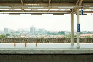 Ilustrasi: Peron stasiun kereta api yang sepi dengan latar belakang pemandangan kota.