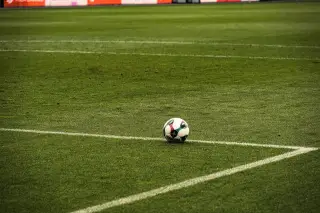 Ilustrasi: Sebuah bola sepak tergeletak di atas garis putih lapangan rumput hijau.