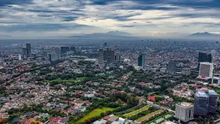 Ilustrasi: Pemandangan udara bentang perkotaan luas dengan gedung-gedung dan latar pegunungan.