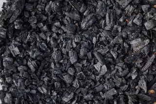 Ilustrasi: Tumpukan pecahan arang kayu atau batu bara berwarna hitam pekat.