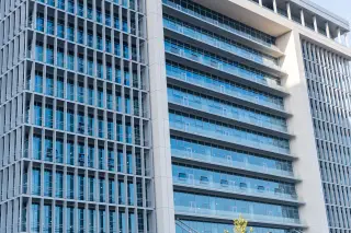 Ilustrasi: Fasad gedung perkantoran modern bertingkat dengan jendela kaca besar.