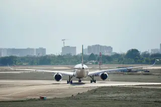 Ilustrasi: Tampak belakang pesawat komersial sedang melaju di landasan pacu bandara.