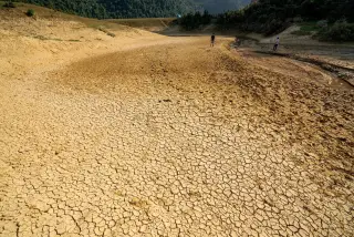 Ilustrasi: Hamparan tanah kering retak dengan dua orang tampak berjalan di kejauhan.