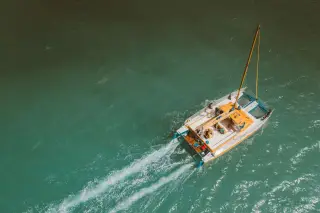 Ilustrasi: Pemandangan dari atas sebuah kapal katamaran yang berlayar di atas laut berair toska.