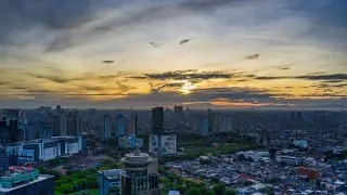 Ilustrasi: Pemandangan udara lanskap perkotaan dengan gedung bertingkat dan permukiman saat matahari terbenam.