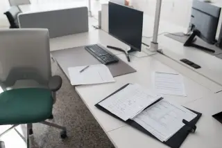 Ilustrasi: Meja kerja kantor modern yang kosong lengkap dengan komputer, kursi, dan dokumen.