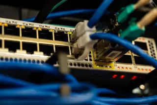 Ilustrasi: Kabel jaringan terpasang pada port perangkat switch server dengan lampu indikator menyala.