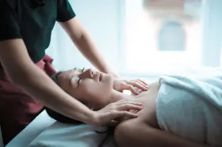 Ilustrasi: Seorang wanita sedang menerima pijatan relaksasi di bagian leher dan pundak di sebuah spa.