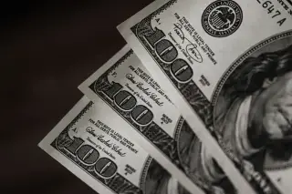 Ilustrasi: Tiga lembar uang kertas pecahan seratus dolar AS tersusun rapi secara bertingkat.