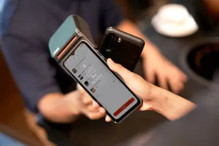 Ilustrasi: Seseorang mendekatkan ponsel pintar ke mesin POS untuk pembayaran digital nirkabel.