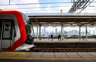 Ilustrasi: Kereta LRT modern berhenti di peron stasiun dengan latar belakang deretan gedung perkotaan.