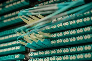 Ilustrasi: Deretan kabel serat optik terpasang pada port server pusat data.