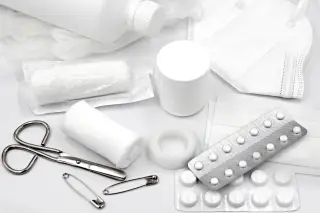 Ilustrasi: Peralatan pertolongan pertama seperti perban, gunting, obat, dan masker di atas latar putih.
