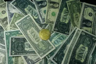 Ilustrasi: Sekeping koin bitcoin emas di atas tumpukan uang kertas satu dolar AS.