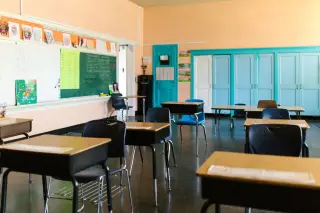 Ilustrasi: Deretan meja dan kursi kosong di dalam sebuah ruang kelas sekolah yang tenang.