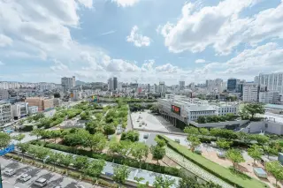 Ilustrasi: Pemandangan luas taman kota hijau di tengah kawasan perkotaan dengan gedung-gedung di bawah langit cerah.