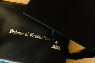 Ilustrasi: Topi toga hitam dengan rumbai bertuliskan 2021 di atas sampul ijazah kelulusan.