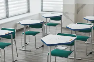 Ilustrasi: Deretan meja dan kursi kosong di dalam ruang kelas yang bersih dan terang.