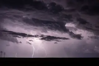 Ilustrasi: Kilatan petir menyambar di langit malam yang tertutup awan badai gelap di atas garis cakrawala.