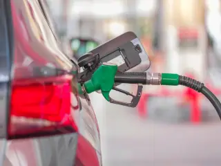 Ilustrasi: Nozel pompa bahan bakar berwarna hijau terpasang pada tangki mobil di stasiun pengisian.