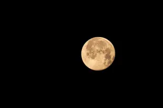 Ilustrasi: Bulan purnama berwarna kekuningan bersinar terang di langit malam yang gelap gulita.