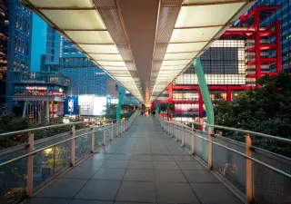 Ilustrasi: Jembatan penyeberangan orang modern dengan lampu menyala di kawasan perkotaan pada senja hari.