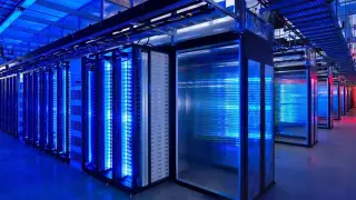 Ilustrasi: Deretan rak server komputer dengan pencahayaan biru terang di dalam pusat data.