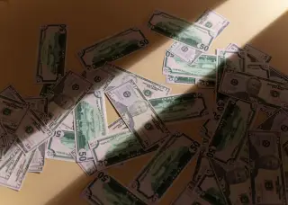 Ilustrasi: Tumpukan uang kertas pecahan 50 dolar Amerika Serikat yang tersebar di atas permukaan datar.