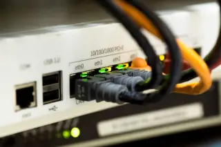 Ilustrasi: Kabel jaringan terpasang pada port router dengan lampu indikator menyala hijau.