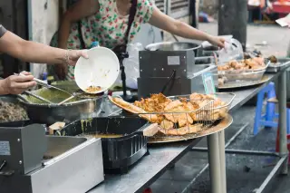 Ilustrasi: Penjual menyiapkan aneka gorengan di atas meja gerai makanan jalanan.