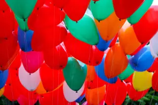 Ilustrasi: Banyak balon warna-warni beraneka bentuk yang diikat dengan tali tipis.