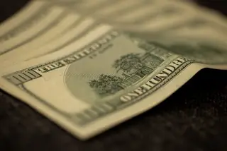 Ilustrasi: Beberapa lembar uang kertas pecahan seratus dolar AS tergeletak di atas permukaan datar.