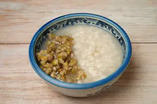 Ilustrasi: Semangkuk bubur kacang hijau dan jelai di atas meja kayu.