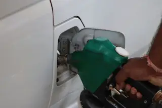 Ilustrasi: Tangan seseorang memegang nozel hijau saat mengisi bahan bakar ke tangki mobil putih.