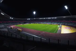 Ilustrasi: Pemandangan stadion sepak bola dengan lampu sorot menyala di malam hari.