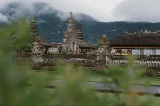 Ilustrasi: Pura tradisional Bali dengan latar belakang perbukitan berkabut.