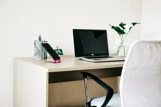 Ilustrasi: Meja kerja modern dengan laptop terbuka, ponsel pintar, alat tulis, dan tanaman hias.