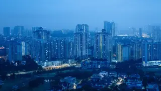 Ilustrasi: Pemandangan lanskap kota dengan gedung-gedung bertingkat pada malam hari bernuansa biru.