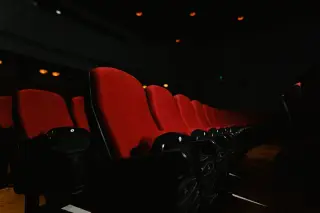 Ilustrasi: Deretan kursi bioskop berwarna merah dalam ruangan teater yang gelap.