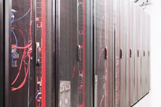 Ilustrasi: Deretan lemari rak server pusat data dengan pintu jaring dan kabel berwarna.