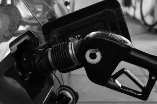 Ilustrasi: Foto hitam-putih nozel pompa bensin yang sedang mengisi tangki bahan bakar mobil.
