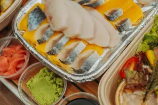 Ilustrasi: Sajian aneka irisan sashimi ikan mentah lengkap dengan wasabi dan acar jahe dalam wadah.