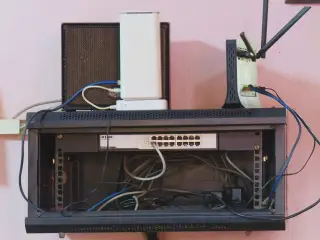 Ilustrasi: Sebuah rak sakelar jaringan internet dengan kabel ethernet dan modem di atasnya.