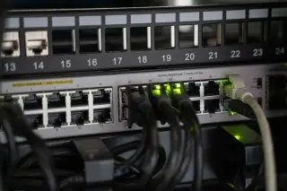Ilustrasi: Kabel jaringan terpasang pada port perangkat switch server dengan lampu indikator menyala.