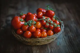 Ilustrasi: Tomat-tomat merah segar dalam keranjang anyaman di atas meja kayu.