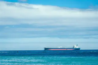 Ilustrasi: Sebuah kapal tanker berlayar di laut lepas di bawah langit biru berawan.