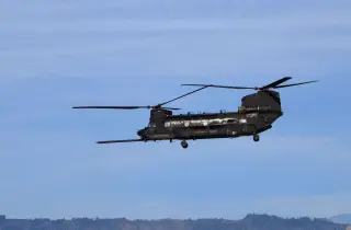 Ilustrasi: Sebuah helikopter militer Chinook terbang di langit berlatar perbukitan.