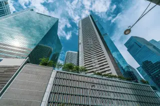 Ilustrasi: Gedung-gedung pencakar langit modern menjulang tinggi dengan latar langit berawan.
