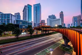 Ilustrasi: Jembatan penyeberangan orang pinisi dan gedung-gedung bertingkat di Jakarta saat senja.