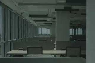 Ilustrasi: Ruangan kantor modern yang luas dan kosong dengan deretan meja kerja serta jendela besar.